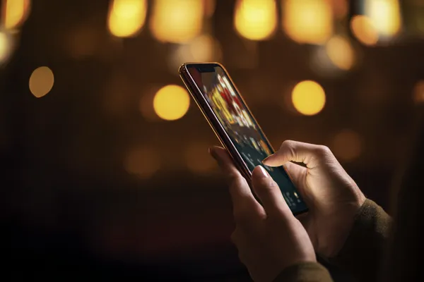A woman smiling by bright slot machines showing lucky symbols, showcasing the exciting slot offerings at TAS71.